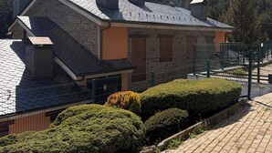 A stone building with a sloped roof, a fenced area, and a well-maintained hedge. - 120 La Molina · Panoramic Views 5 Minutes From La Molina Ski Resort (Alp)