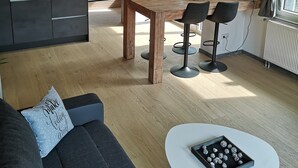 Un saló modern amb un sofà, una taula de centre i una zona de menjador amb taula i cadires.