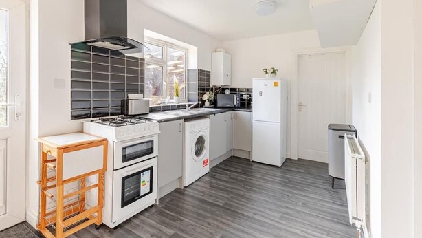 Una cocina moderna equipada con estufa a gas, horno, microondas y lavadora.