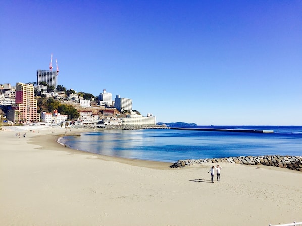 A beach with a cityscape in the background, including a prominent building with a red spire.