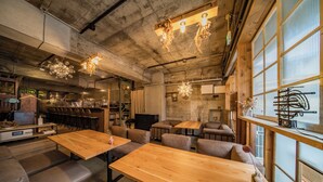 A restaurant with wooden tables and booths, hanging light fixtures, and large windows. - ArtBar & GuestHouse ennova - Hostel (Atami)