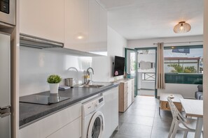 Eine moderne Küche mit Einbauwaschmaschine, Spüle und Essbereich mit Tisch und Stühlen.