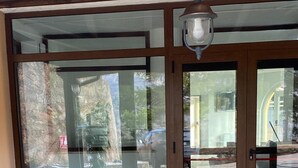 A building entrance with large glass doors, a tiled floor, and a hanging light fixture.