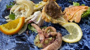 A variety of dishes on plates, including seafood and salads.