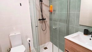 Un bagno moderno con doccia vetrata, servizi igienici, lavandino e specchio.
