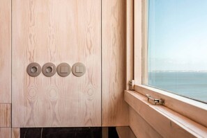A bathroom with a wooden vanity, a window with a view of the sea, and a set of four light switches. - Mivô | Panoramic Lisbon View · (Alfama/Cathedral) (Lisbon)