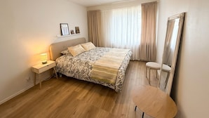 A bedroom with a bed, bedside table, lamp, chair, and a mirror. - Relaxing Riverside House with Sauna & Fireplace (Kannus)