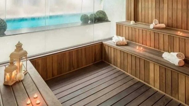 A wooden spa room with a large window, a bench, and a small table with candles. - Apartment for 4 people in Bombas + swimming pools + gym + sauna + games rooms (Bombinhas)