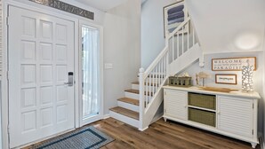 A staircase with a white railing, a white door with a number plaque, and a welcome sign above the stairs. - Spacious and modern 3 bedroom villa with stunning lagoon views (Hilton Head Island)