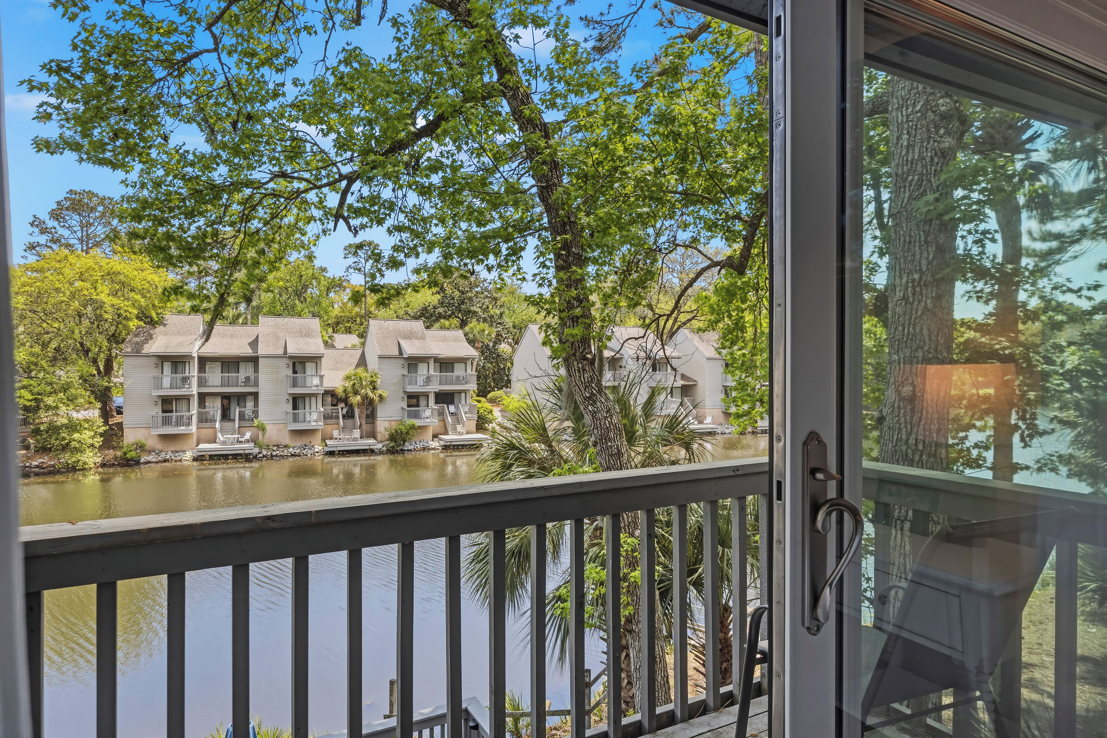 A view of a building with multiple balconies and a water body in the foreground.