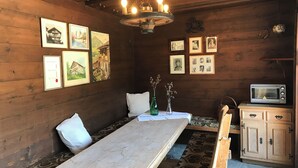 Ein Holzinterieur mit einem langen Esstisch, Bildern an der Wand, einer Deckenleuchte und einer Mikrowelle.