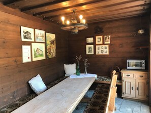 En inredning med trädetaljer, ett långt matbord, tavlor som hänger på väggen, en kristallkrona och en mikrovågsugn.