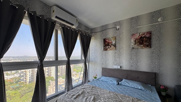 Ein Schlafzimmer mit einem großen Bett, einem Fenster mit Vorhängen und zwei Wand-Klimaanlagen.