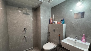 Ein modernes Badezimmer mit Dusche, Toilette und Waschbecken, mit Marmorwänden und zeitgemäßem Design.
