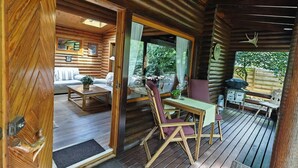 A wooden cabin interior with a dining area, a sofa, and a view through a window.