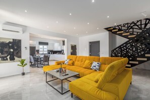 A modern living room with a sectional sofa, a coffee table, and a staircase with a geometric design. - Villa Mirela - Perfect Family escape With  Private Pool, BBQ & Fenced Yard (Šišan)