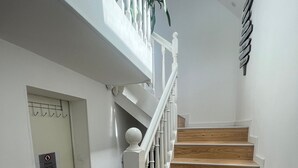 Eine Treppe mit Holzdielen und weißen Spindeln, die zu einer Empfangshalle mit einer Tür mit der Aufschrift 'Privé' führt.
