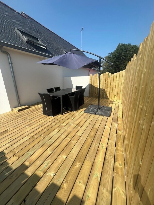 Eine Terrasse im Freien mit Tisch und Stühlen, einer Holzterrasse und einem Holzzaun.