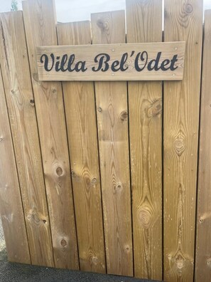 Une clôture en bois sur laquelle est apposée une plaque portant l’inscription « Villa Bel’Odet ».