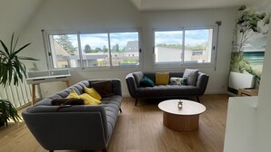Ein modernes Wohnzimmer mit zwei Sofas, einem Couchtisch und großen Fenstern.