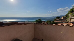 Terraço com vista para um corpo de água e montanhas ao longe.