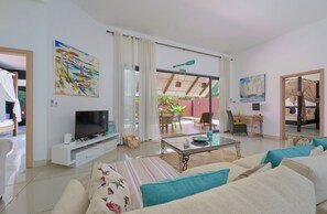 A spacious living room with a TV, sofa, coffee table, and artwork. - Villa Coco Chic- Private pool - Tropical garden (Pointe aux Piments)