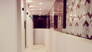 Um corredor com paredes brancas, piso de mármore e azulejos decorativos.