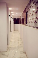 Un pasillo con paredes blancas, suelo de mármol y azulejos decorativos.