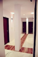 Un pasillo con paredes blancas, piso de madera y puertas de madera oscura.