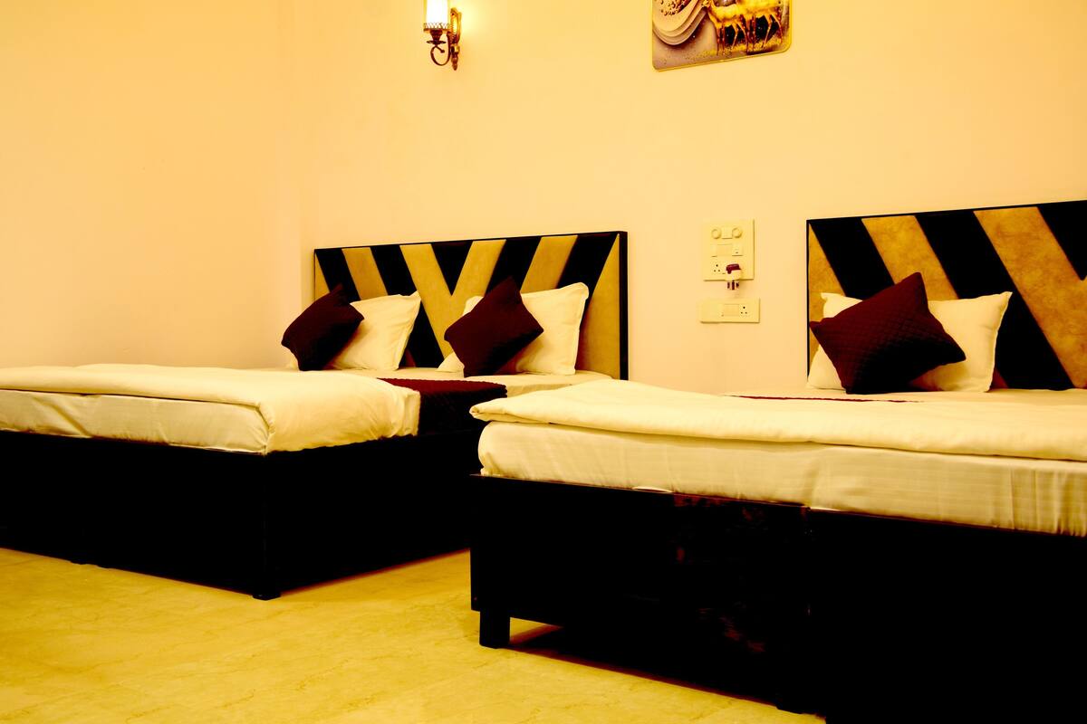 Two single beds with black and gold headboards, white bedding, and a wall-mounted light fixture.
