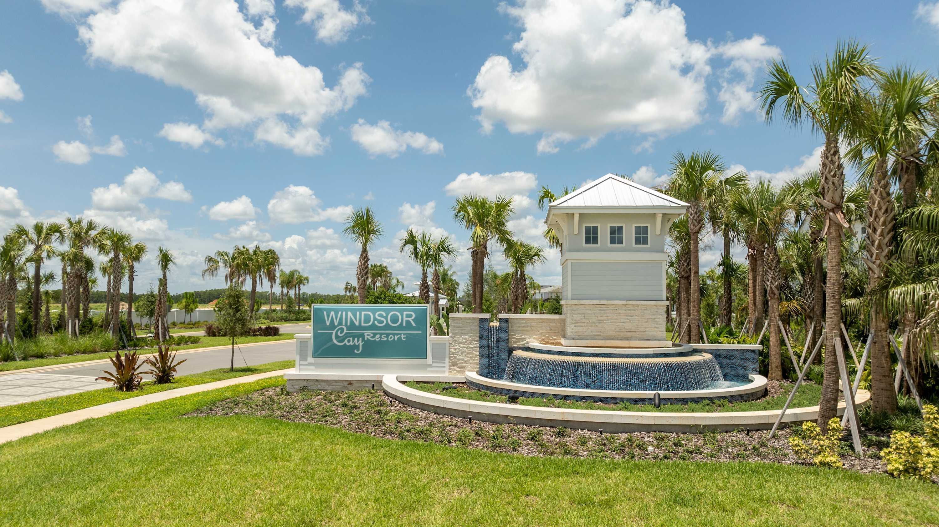 A resort sign with a pool area and palm trees.
