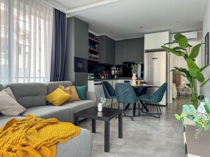 Un salon moderne avec un canapé gris, une table basse et un coin repas avec des chaises.