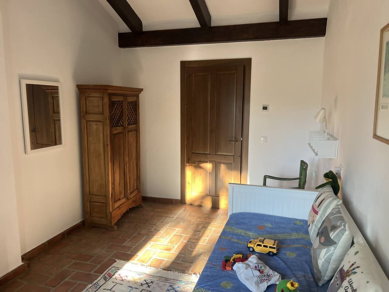 Ein Zimmer mit einem Bett, einem Kleiderschrank und einer Tür zu einem anderen Raum.