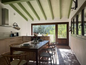 Una cocina con mesa, sillas y vistas amplias por un ventanal.