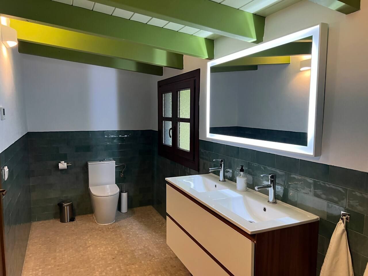 Un bagno moderno con un lavabo doppio, un water e uno specchio sopra il lavabo.