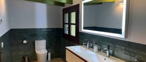 Un bagno moderno con un lavabo doppio, un water e uno specchio sopra il lavabo.