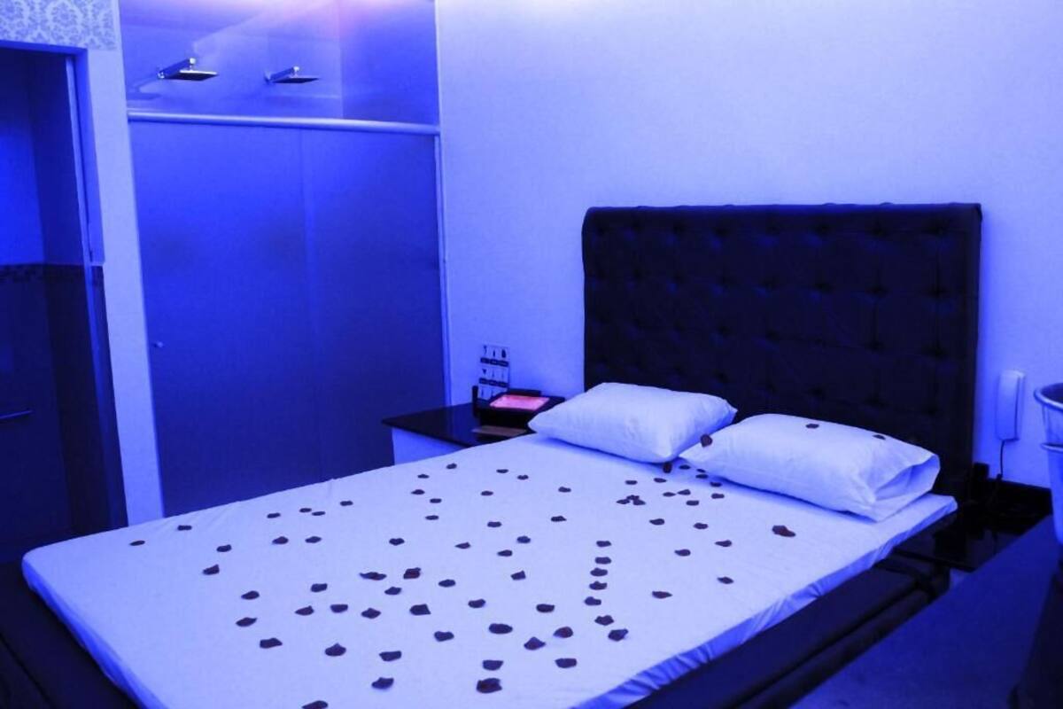 Una habitación de hotel con una cama, una mesita de noche y un armario.