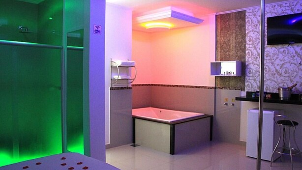 A bathroom with a bathtub, a shower, a vanity with a mirror, and a toilet. - Motel hotel Vitória  (Rialma)