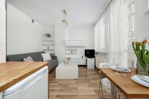 Moderni olohuone, jossa on sohva, sohvapöytä, televisio sekä ruokailutila tuoleineen ja pöytineen.