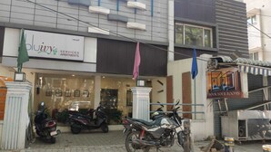Un immeuble avec une enseigne indiquant « Bluivy Serviced Apartments » et une autre enseigne indiquant « Réservez vos chambres ». On peut voir des scooters et une moto garés devant.