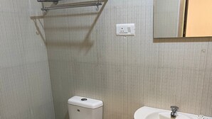 Une petite salle de bain avec des toilettes, un lavabo et un porte-serviettes.
