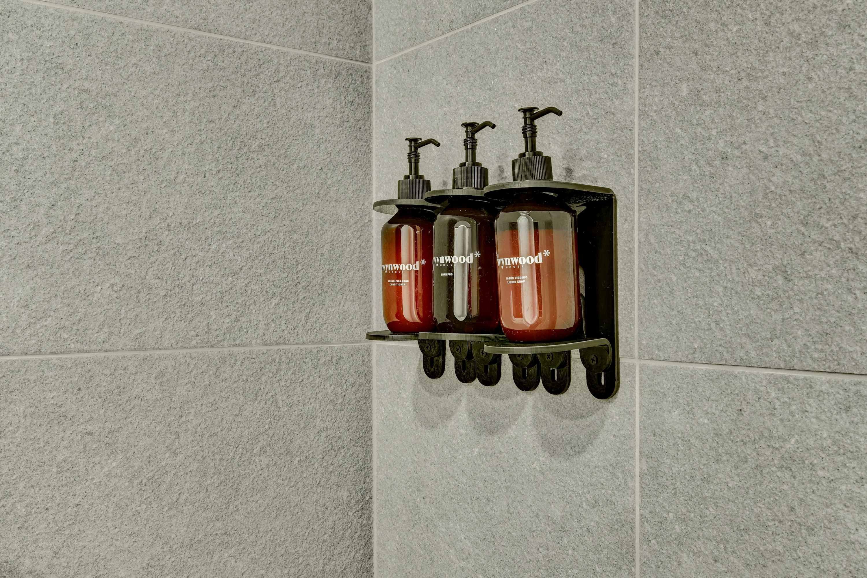 Ein Badezimmer mit Wandseifenspender und Ablage für drei Flaschen.