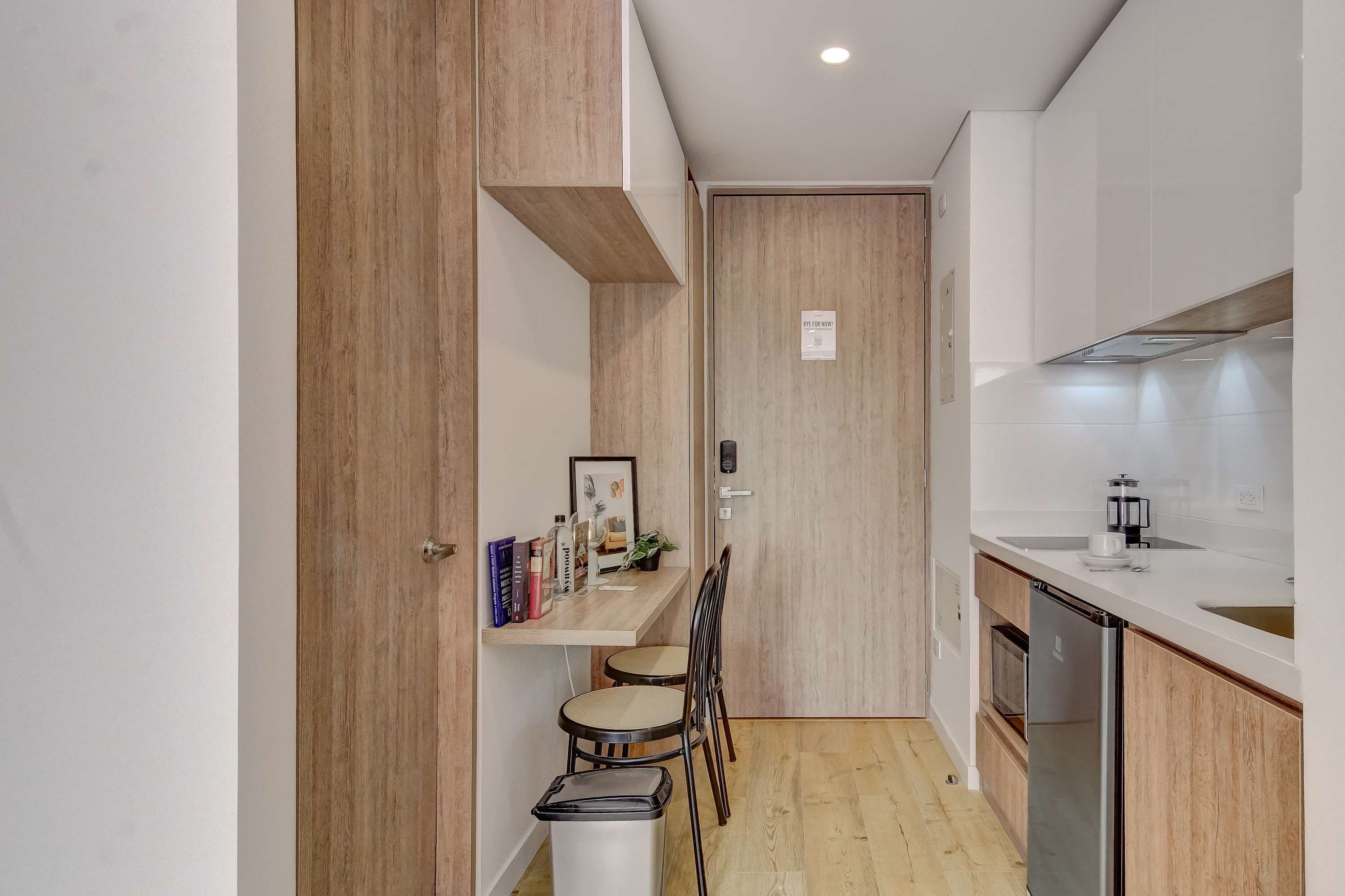 Une cuisine compacte avec des meubles en bois, un lave-vaisselle encastré et un petit coin repas comprenant une chaise et une table.