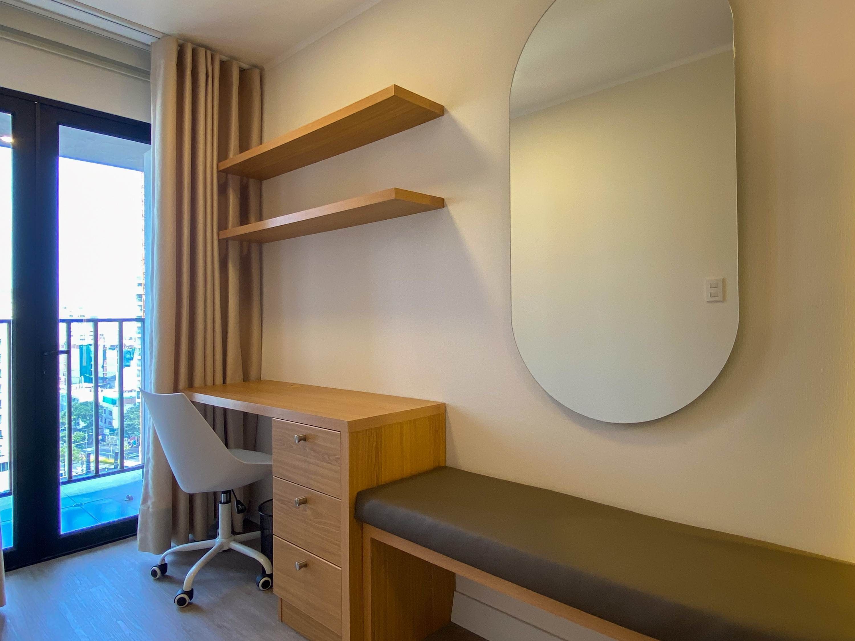 A modern bedroom with a desk, chair, and a large mirror.