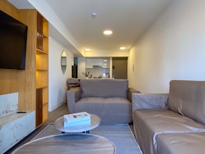 Uma sala de estar moderna com um sofá, uma mesa de centro e uma televisão fixada na parede.