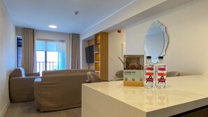 A modern living room with a sofa, a coffee table, a TV, and a sign indicating the room is part of a hotel. - w Luxury 3BR w Balcony in Upscale Miraflores (Lima)