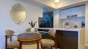 A modern kitchen with a glass dining table, wooden chairs, a vase with greenery, and a large mirror on the wall. - w Luxury 3BR w Balcony in Upscale Miraflores (Lima)