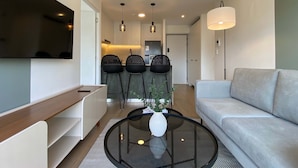 A modern living room with a sofa, a coffee table with a vase, and a TV mounted on the wall. - w Deluxe 2BR w Balcony View in Miraflores (Lima)