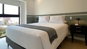 A modern bedroom with a large bed, a nightstand, a lamp, and a view of the outside. - w Deluxe 2BR w Balcony View in Miraflores (Lima)