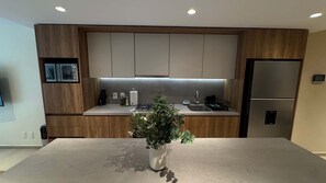 A modern kitchen with wooden cabinets, a stainless steel refrigerator, and a central island with a potted plant. - w Welcoming 2BR w Private Terrace in Hipodromo (Mexico City)